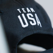 Load image into Gallery viewer, Up close view of the back closure of a navy baseball hat with Team USA embroidered just above the closure
