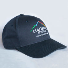 Load image into Gallery viewer, Side view of navy baseball hat with Colorado Springs:Olympic City USA embroidered on the front. Hat sitting in white background.
