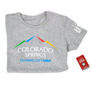 Horizontally folded in half gray short sleeved t-shirt with full color version of the city of Colorado Springs: Olympic City USA logo. Team USA printed in white on the right sleeve. Team USA tag attached.