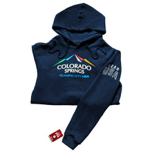 Load image into Gallery viewer, Folded horizontally in half navy pullover hoodie with hoodie strings attached to hood. Color version of the city of Colorado Springs: Olympic City USA logo printed in center. Team USA printed in white omn the upper right sleeve. Team USA tag attached to bottom of same sleeve.
