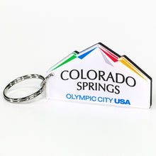 Load image into Gallery viewer, Custom cut keychain of the city of Colorado Springs: Olympic City USA logo. Silver-colored key ring attached. Custom cut to look like mountains.
