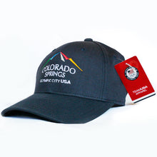 Load image into Gallery viewer, Navy Baseball Hat with the Colorado Springs: Olympic City USA logo embroidered on the front alone in a white background. Team USA Apparel tag attached.
