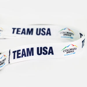 Up close view of the with official City of Colorado Springs: Olympic City USA and Team USA logos and wordmarks decorating a white lanyard